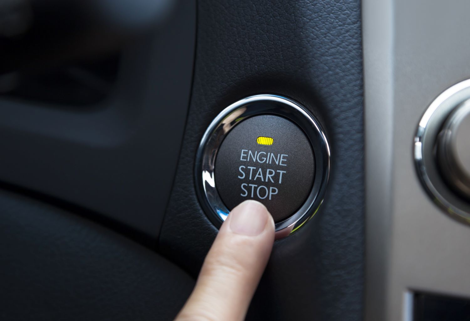 Finger pressing a vehicle's engine start and stop button